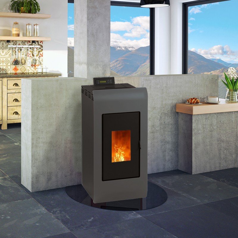 Poêle à granulés Kiara 8 kW avec kit ventouse, installé dans une cuisine moderne avec vue sur des montagnes, flamme visible à tr