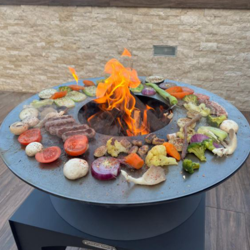 Brasero plancha Fiesta 75 cm en acier corten avec feu central et légumes grillés en situation d'utilisation