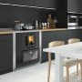 Cuisinière à granulés encastrable moderne intégrée dans une cuisine contemporaine avec meubles noirs et table blanche.