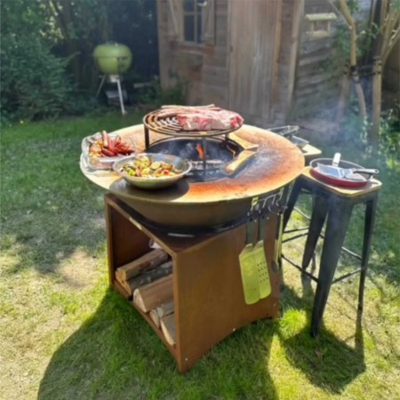 Brasero plancha Brasinox Fiesta en acier corten 75 cm avec grille, en situation dans un jardin