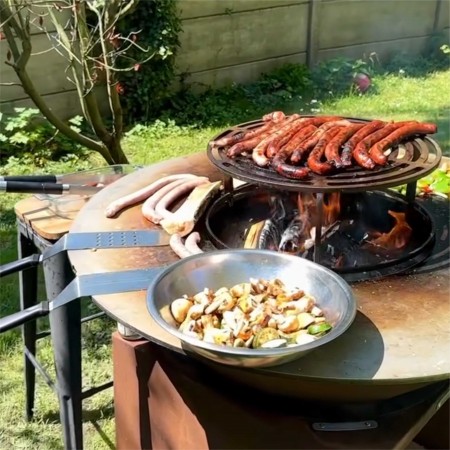Brasero plancha XXL en acier corten avec grille de cuisson et planchas en situation dans un jardin