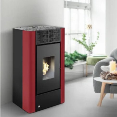 Poêle à granulés 9 kW Maria 2.0, installé dans un salon moderne et lumineux, avec une femme lisant sur un canapé à côté d'une ta