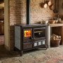 Cuisinière à bois Steel Gardenia XXL noire avec four et foyer allumé dans cuisine rustique