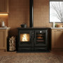 Cuisinière bois Alaska 12 kW noire avec four et foyer allumé, installée dans cuisine moderne
