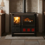 Cuisinière à bois Rosa XXL Steel noire avec four et feu allumé installée dans cuisine rustique