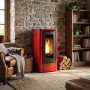 Poêle à granulés Extraflame Teorema Plus rouge 12 kW installé dans salon rustique avec mur en pierre