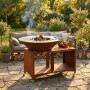 Brasero BBQ plancha Brasinox Fiesta Island Ø75 cm allumé dans un jardin