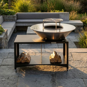 Brasero plancha extérieur Brasinox Fiesta 100 cm installé sur une terrasse avec rangement à bûches