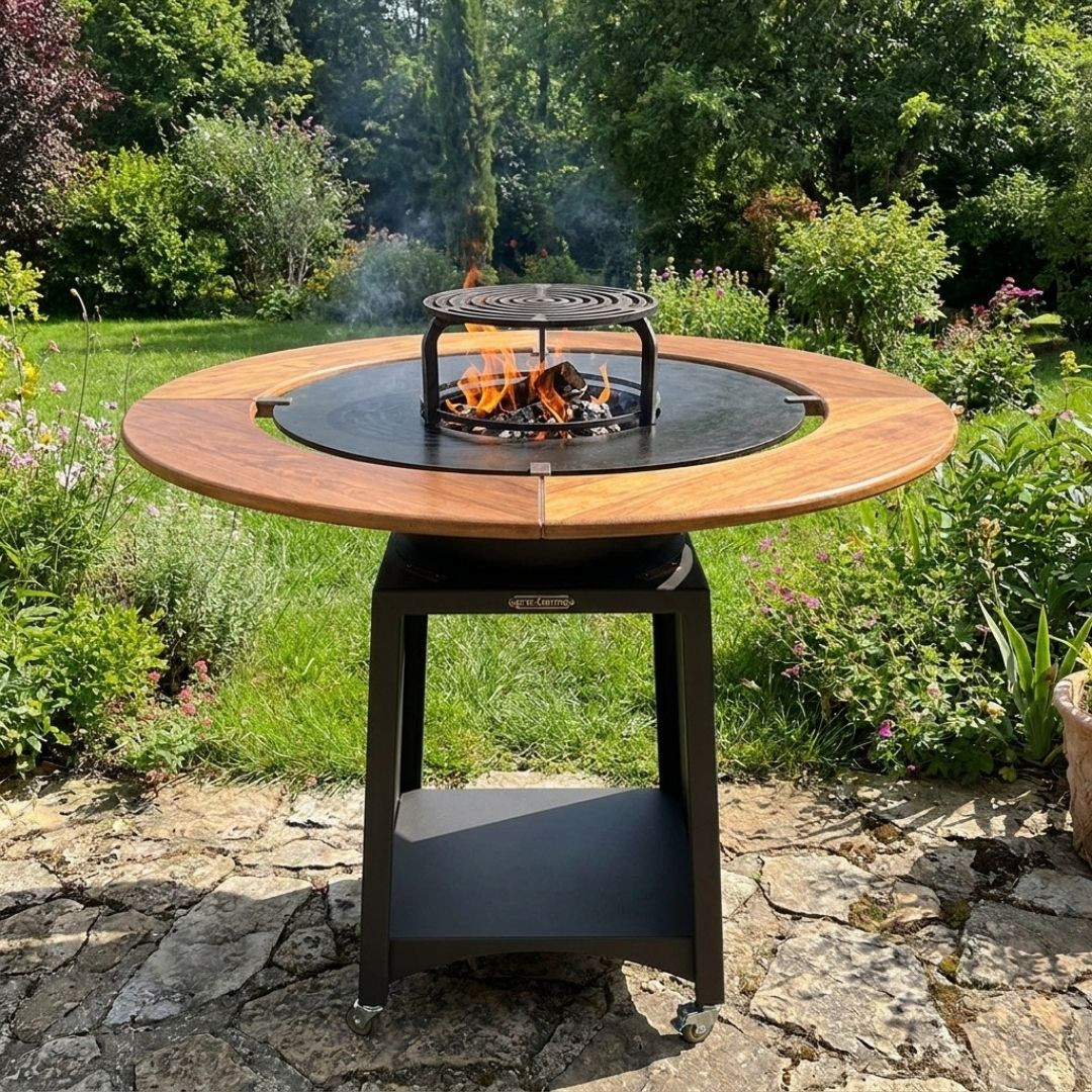 Brasero plancha Kit Fiesta Ø75 cm avec table en bois et feu apparent dans un jardin