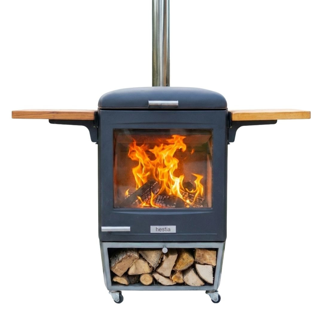 Vue de face du barbecue à bois Hestia 600 Heat & Grill avec foyer allumé, cheminée et rangement pour bûches