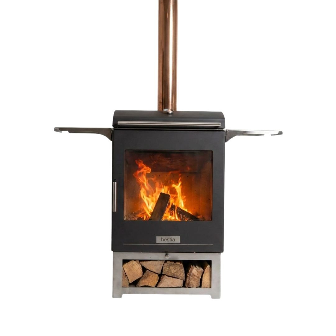 Vue de face du barbecue à bois Hestia 300 Heat & Grill avec foyer vitré allumé, cheminée et rangement pour bûches