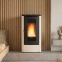 Poêle à granulés canalisable Dahiana Plus AD 10 kW ivoire devant un mur en tasseaux de bois