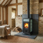 Poêle à bois Gemma Lean Petra 6,5 kW installé dans un salon avec mur en pierre